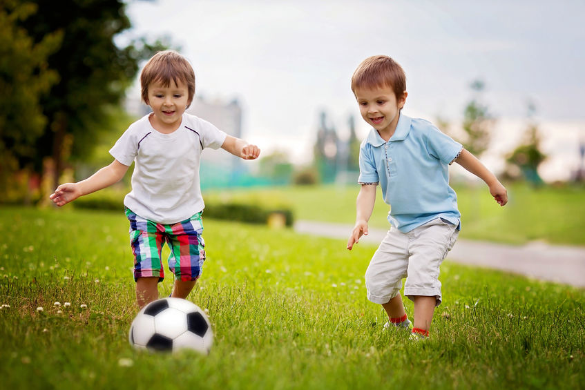 Un niño jugando con una pelota de fútbol en el pasto